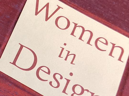 Close up on a book with a pink cover titled Women in Design
